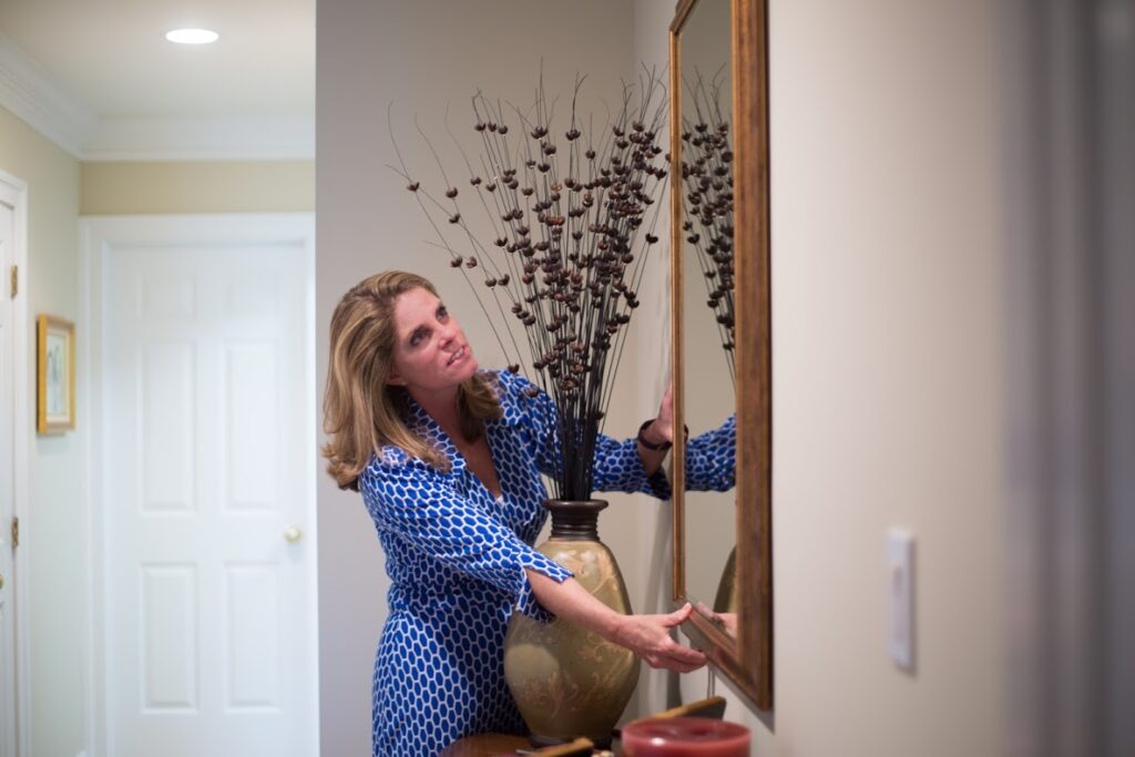 potomac concierge personal assistant adjusting an entry mirror on the wall behind plant on table