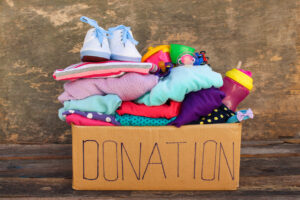 brown cardboard donation box full of young girls clothing